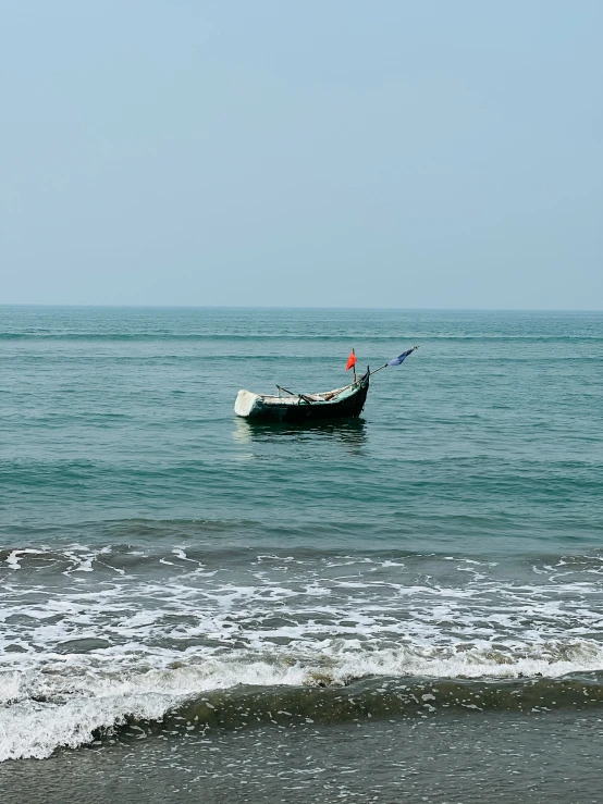 a small boat in the ocean next to a wave