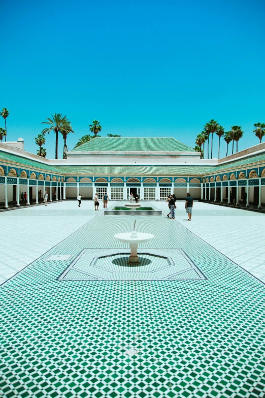 a courtyard with benches, palm trees and blue sky