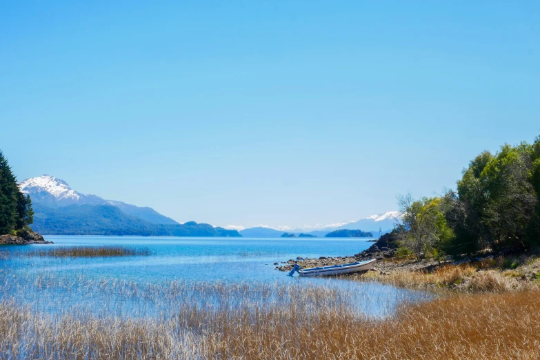 small wooden boat on calm lake with mountains in the distance