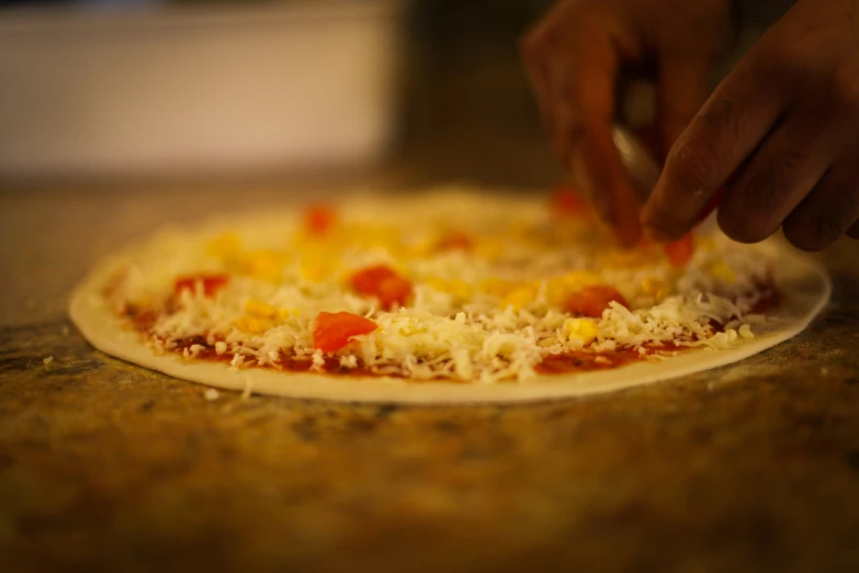 an image of someone putting cheese on top of a pizza