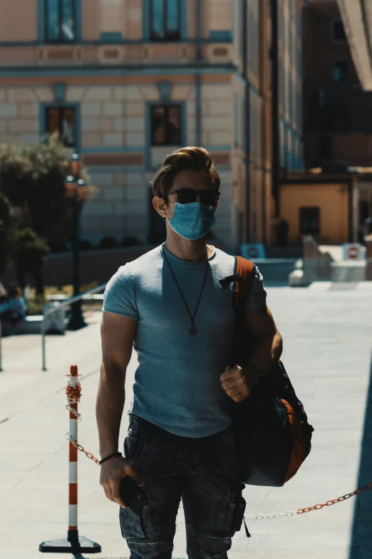 man walking down the sidewalk wearing a mask while carrying a backpack