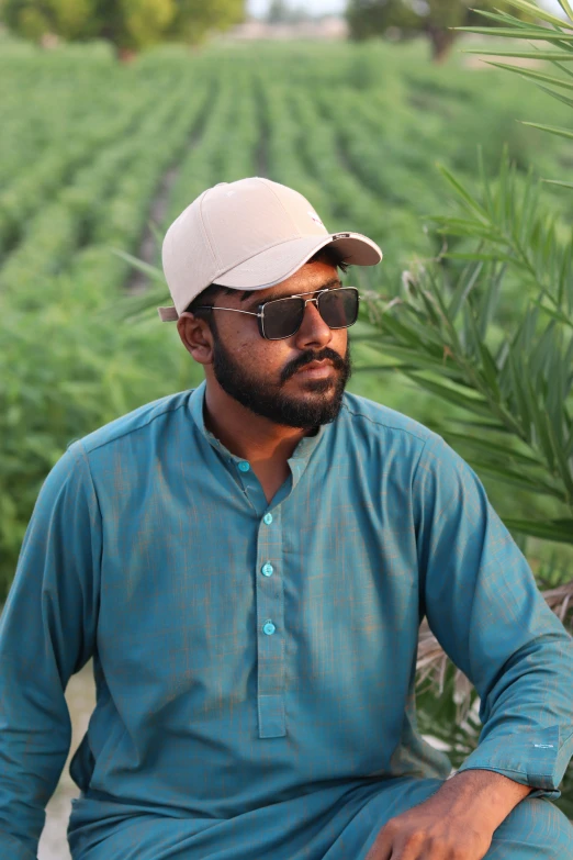 a man sitting in front of a lush green field