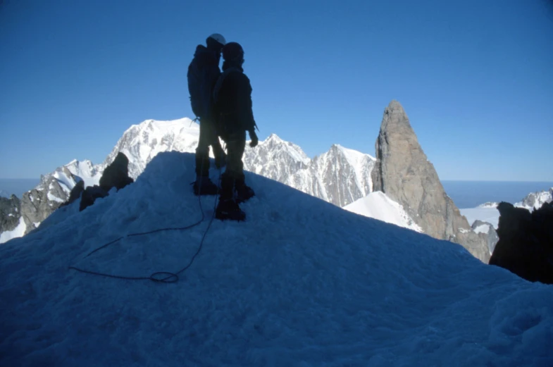 two men on a mountain top with their skiis