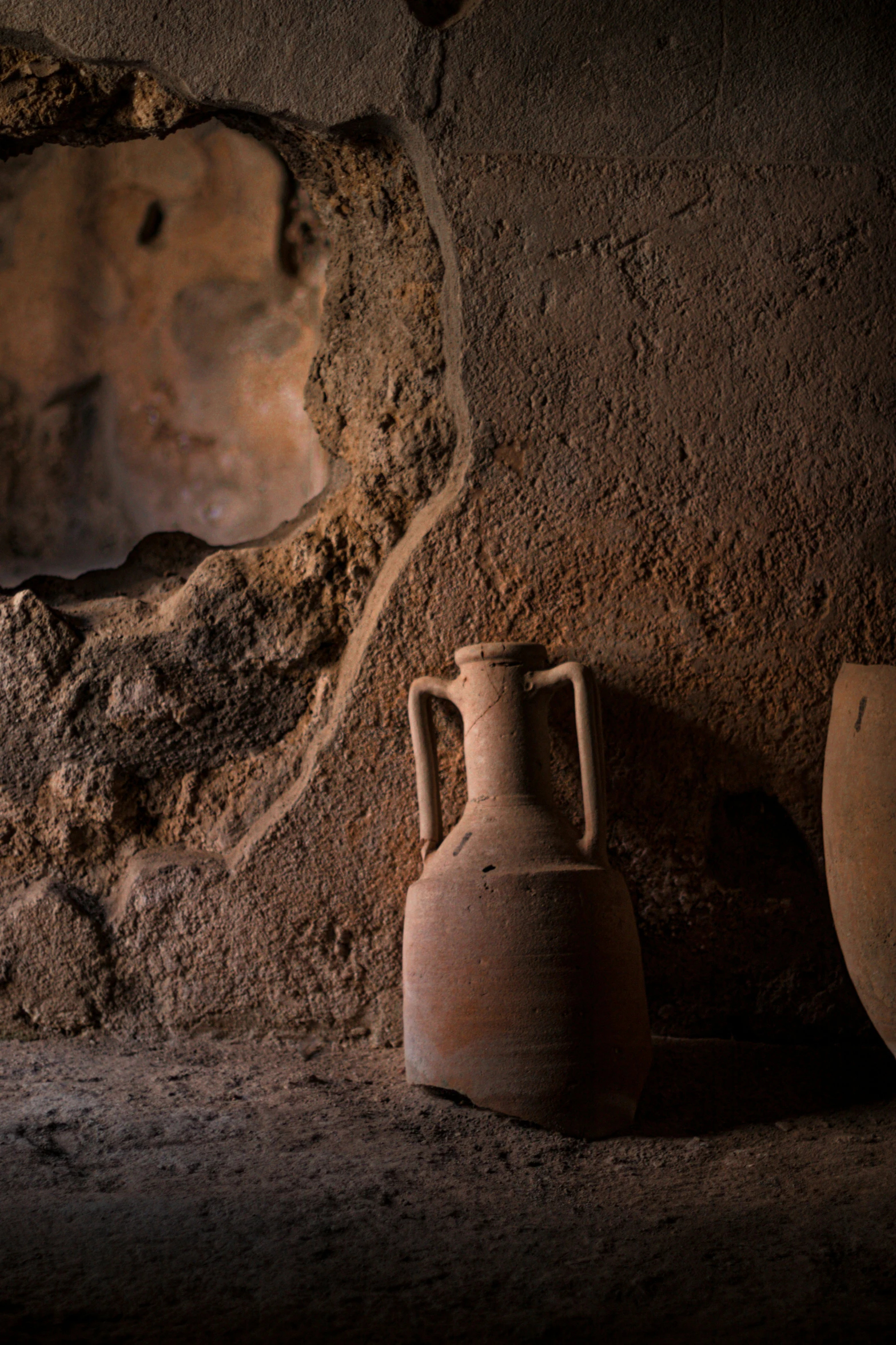 three clay vases are placed against the rock wall