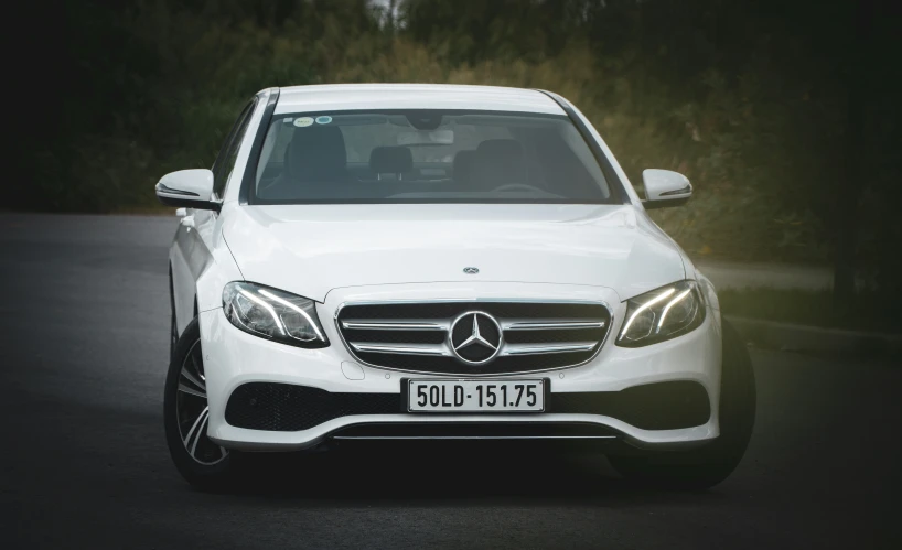 a white mercedes benz is shown driving in the street