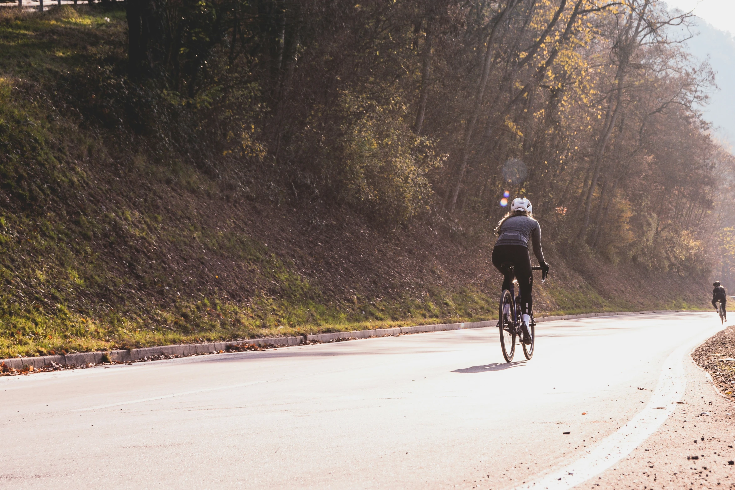 two people riding bikes down a country road