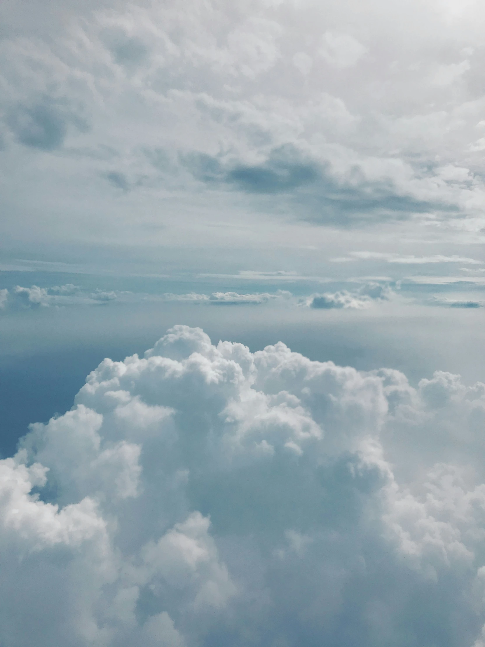 an airplane flies above fluffy clouds in the sky