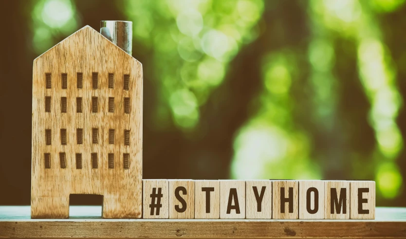 a wooden block spelling the word home next to a house