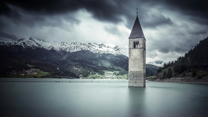 a tall stone tower standing in the middle of water