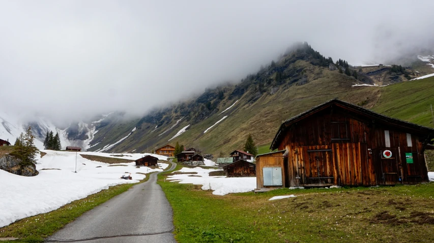 some snow and green grass buildings and hills