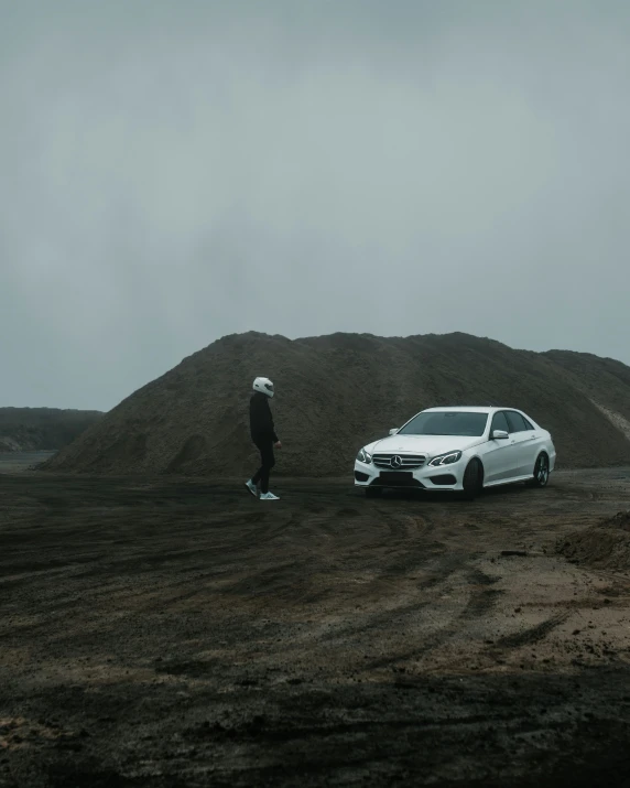 a white car is parked next to a hill