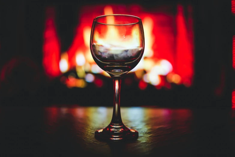 a glass of wine sitting on a table in front of a fire