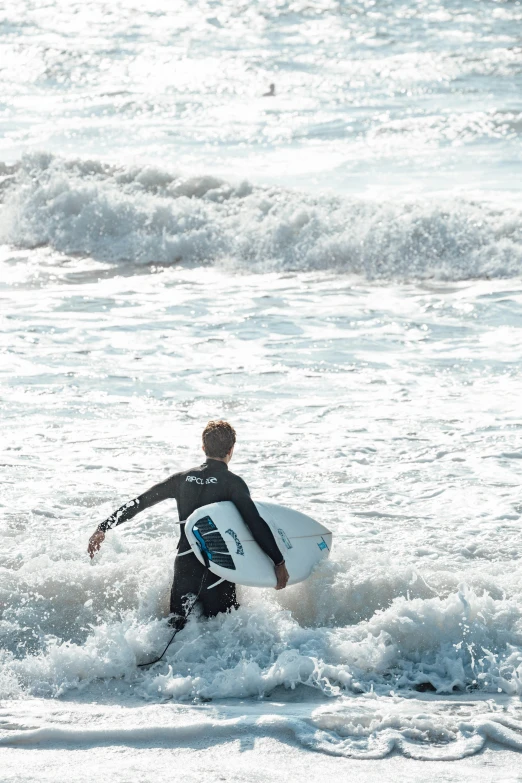 a man holding a surfboard walking into the ocean
