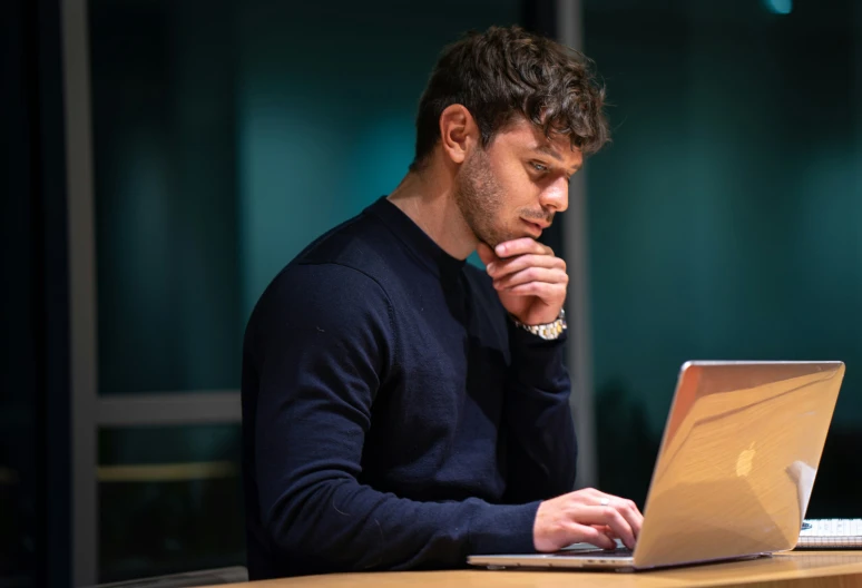 a man holding his hands to his face, while looking at his laptop