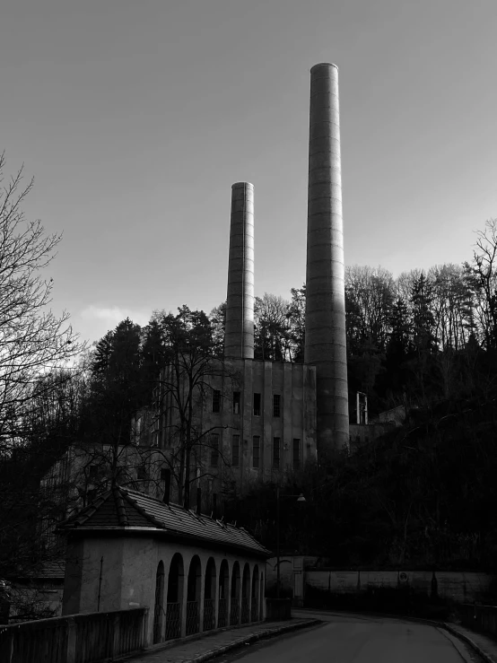 three smokestacks rise above a building on a hill