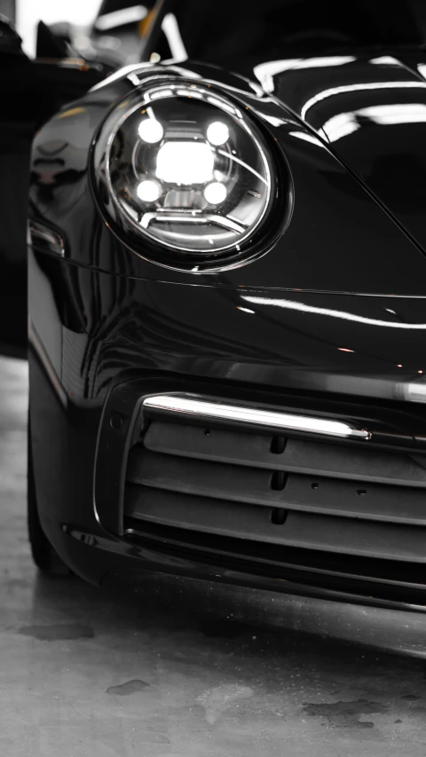 a black car in a garage with a small light on the front of the headlight