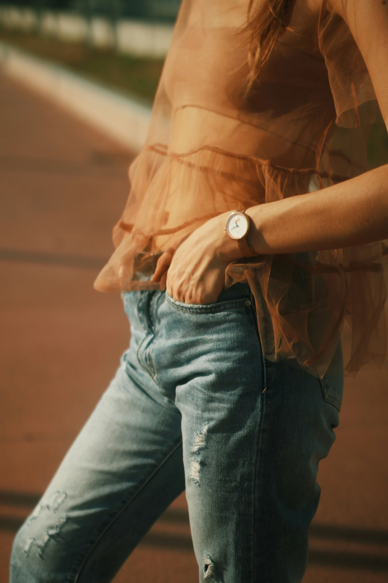 woman wearing a watch and jeans standing on street