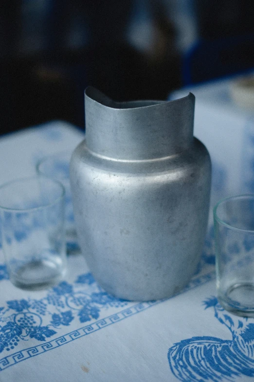 a glass sits on the edge of a silver vase