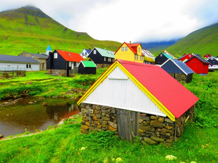 a rural town with red roofing, grassy field and mountain