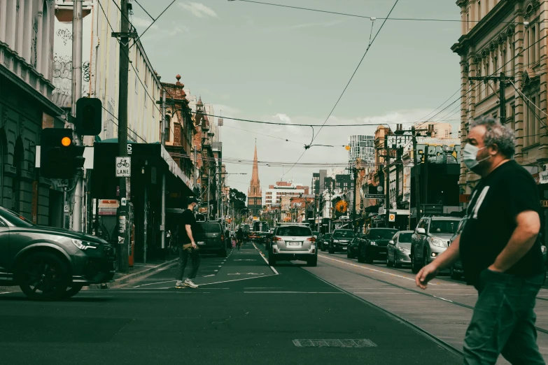 a man with a face mask walks down a busy street