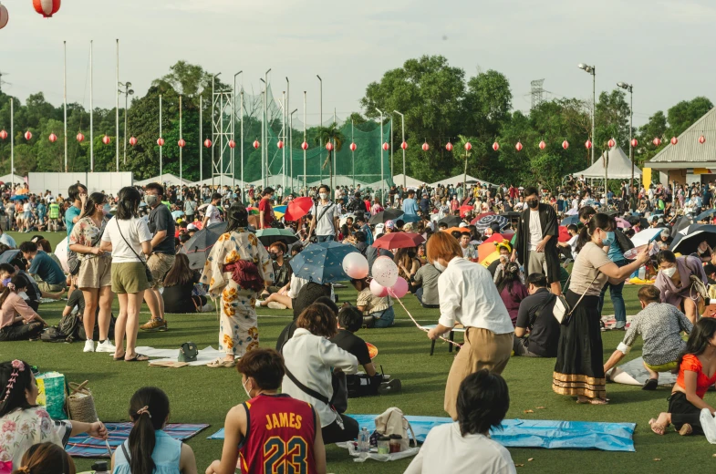 a large crowd of people are gathered at a park for the festival