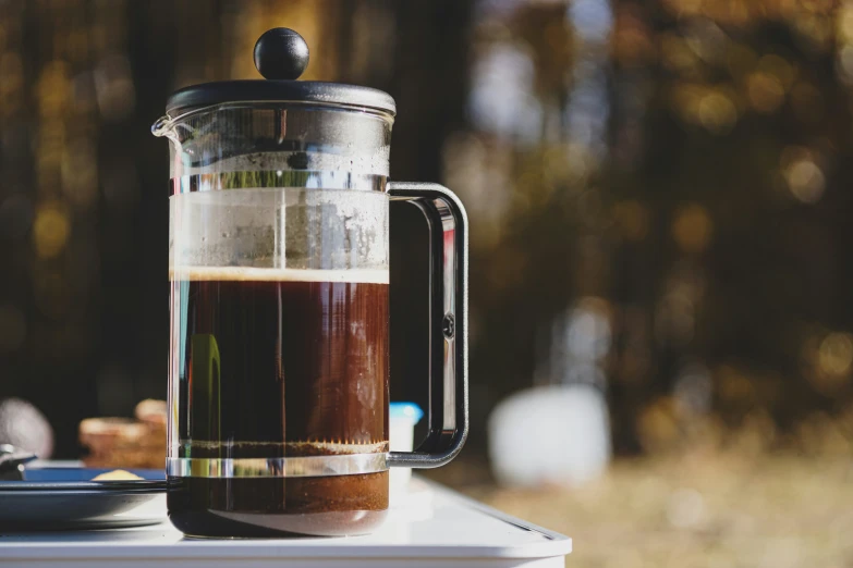 a cup of brown liquid is sitting next to a teapot