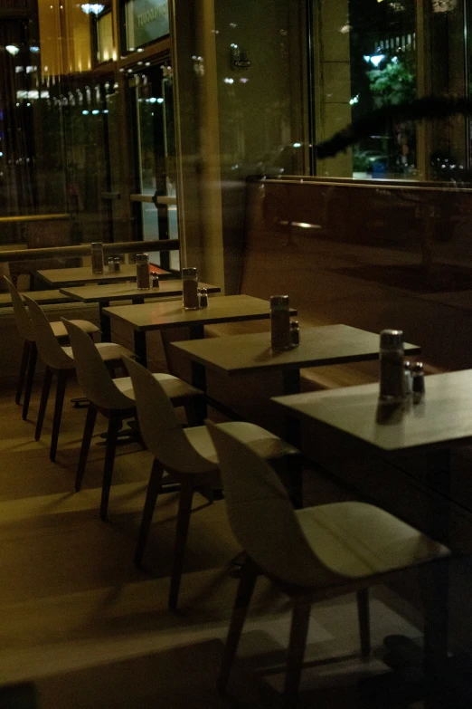 a restaurant table covered in chairs next to a glass wall