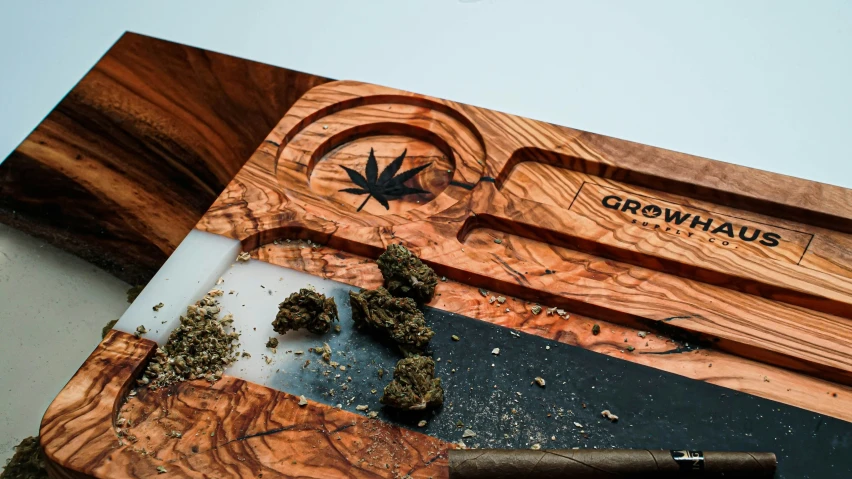 a wooden board holding some marijuana and a knife