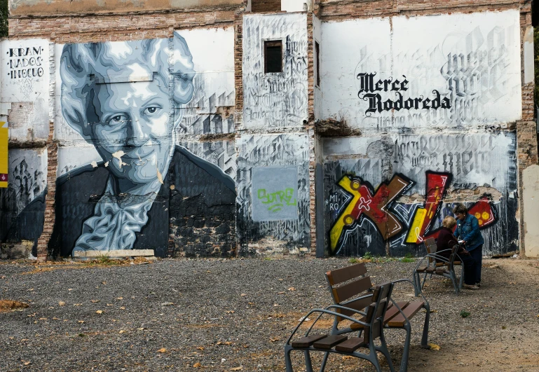 a man sitting on a bench in front of some graffiti