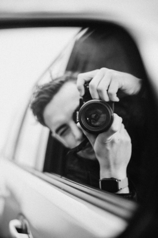 a man looking in a car mirror while taking a selfie