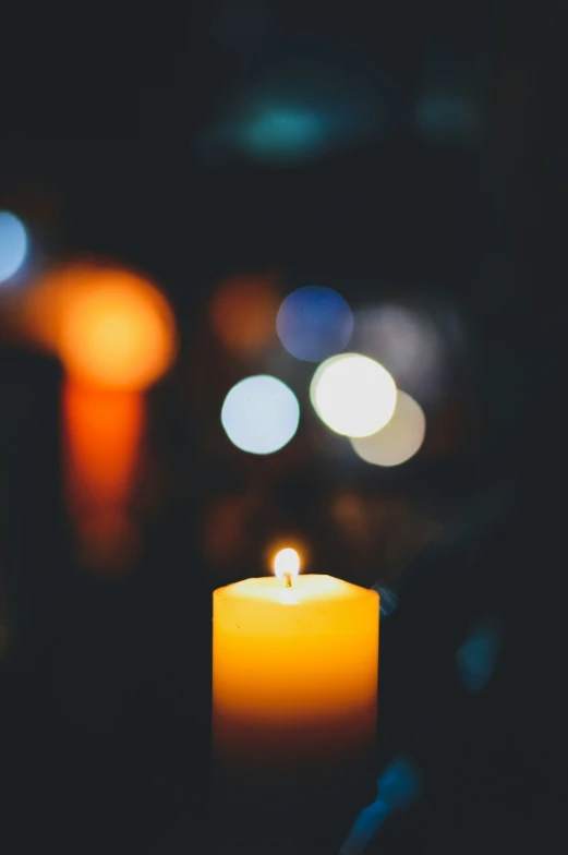 a lit candle with blurred lights on it