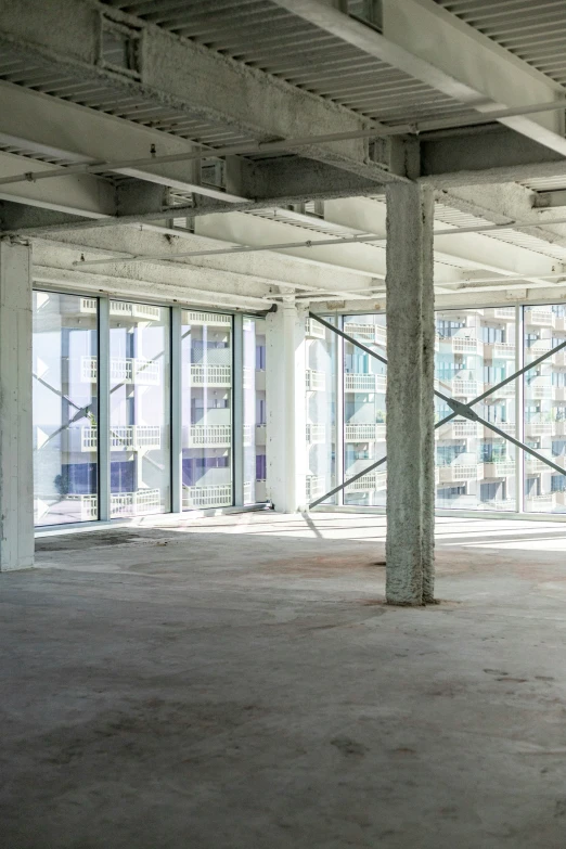 a warehouse building with windows, unfinished floors, and concrete pillars