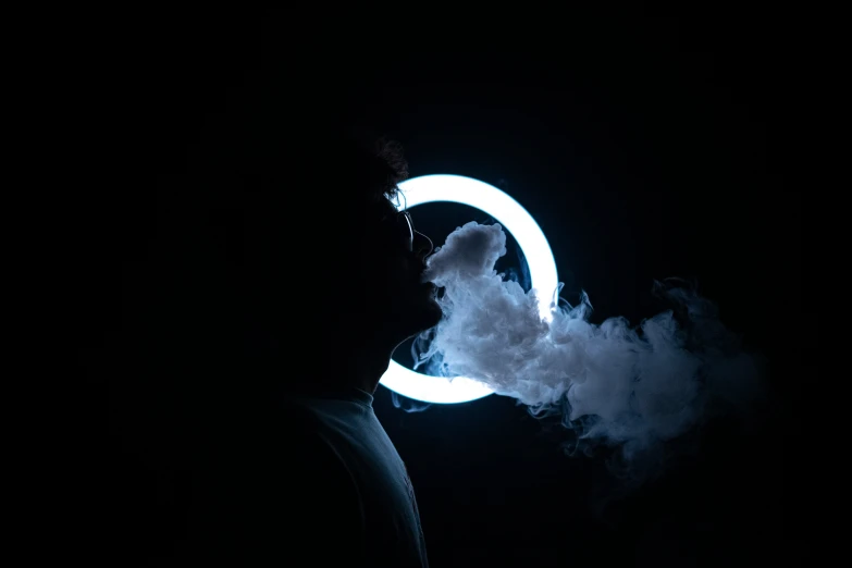 a man is blowing a round shape made out of smoke