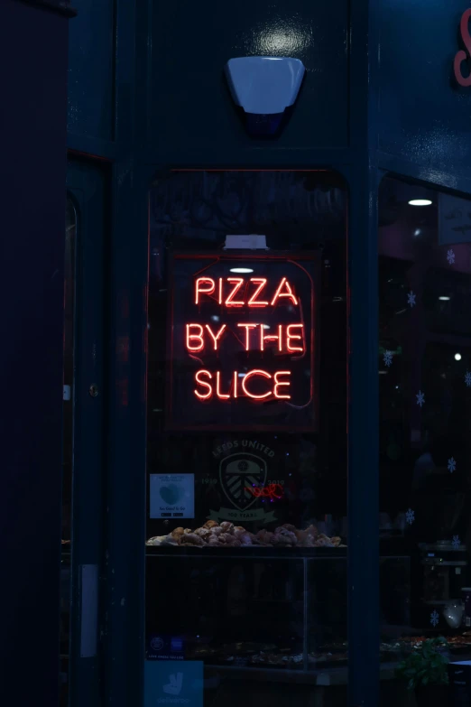 a neon pizza sign sitting on the side of a building