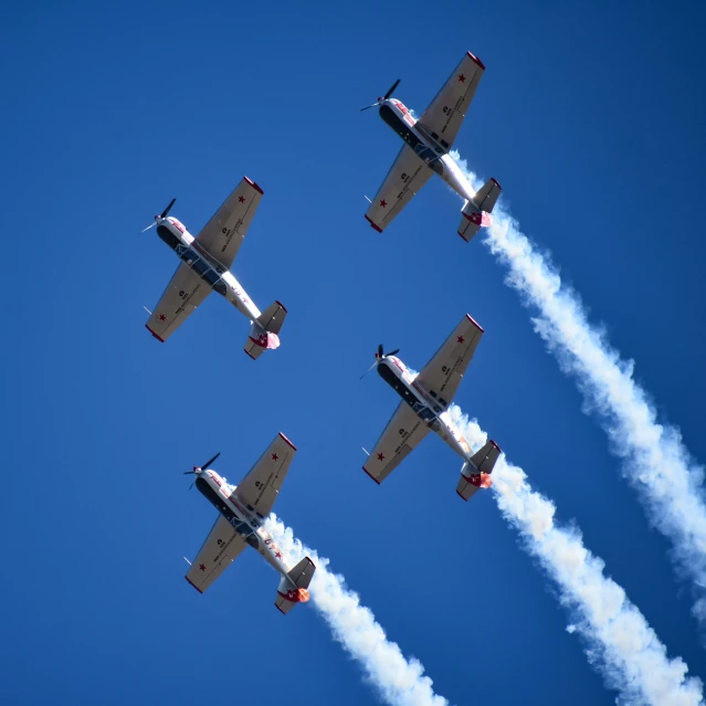 four airplanes flying in formation with smoke coming from them