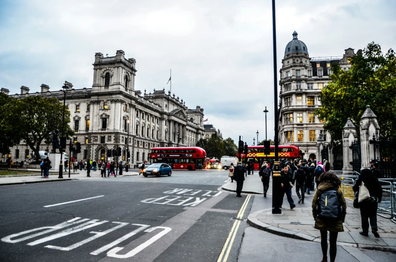 people are crossing the street and busses line the street