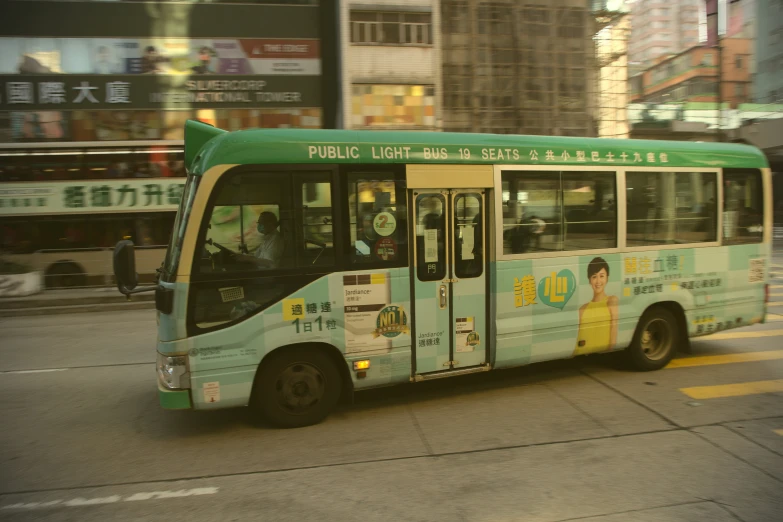 a bus with advertism signs on the front drives down the street