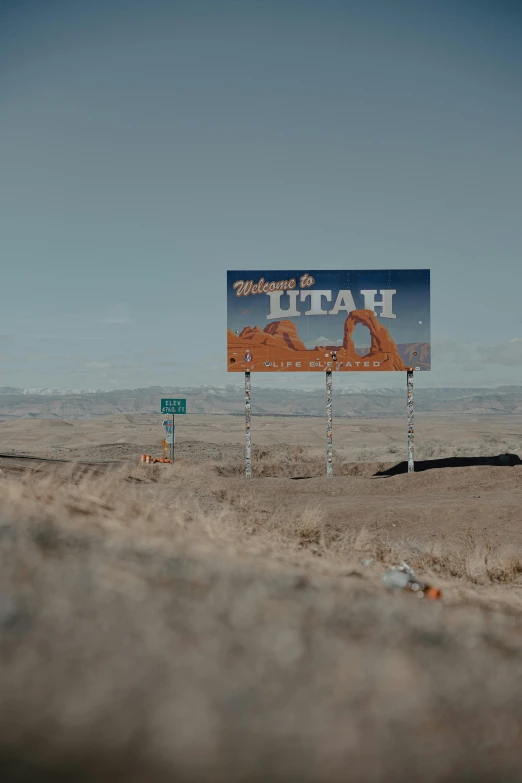 a blue sign sitting on the side of a dirt road