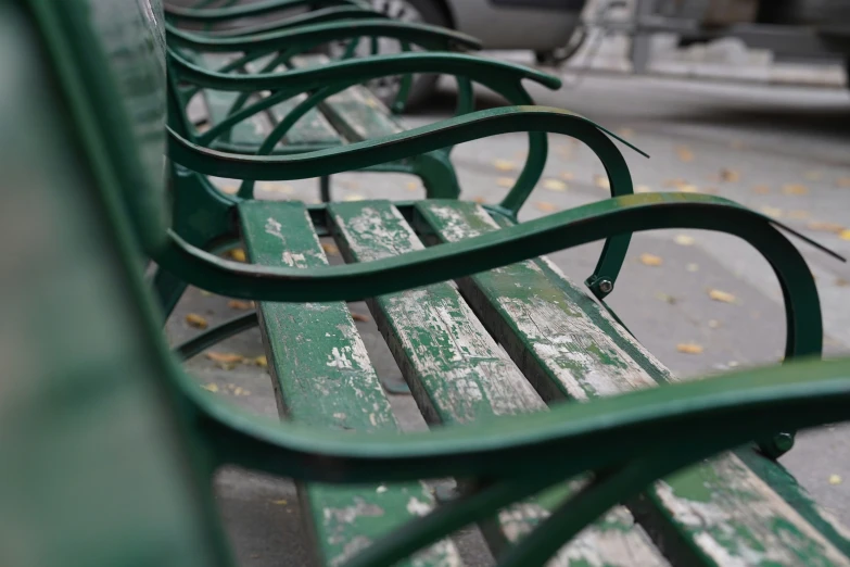 green metal benches sit in the center of an empty park