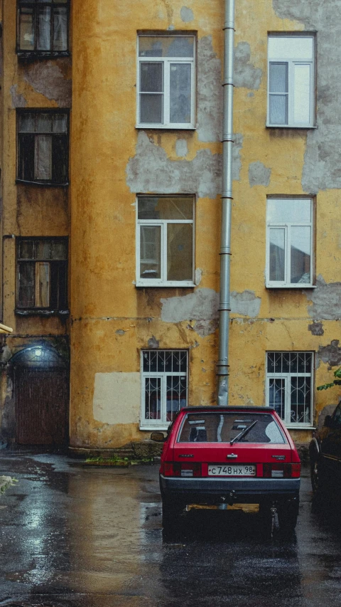 a red car driving in front of an old building