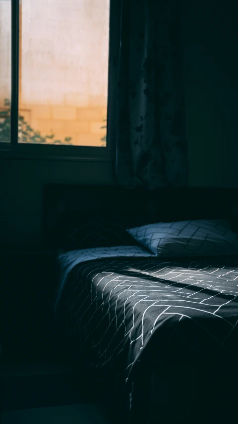 a bed and window in a dimly lit bedroom