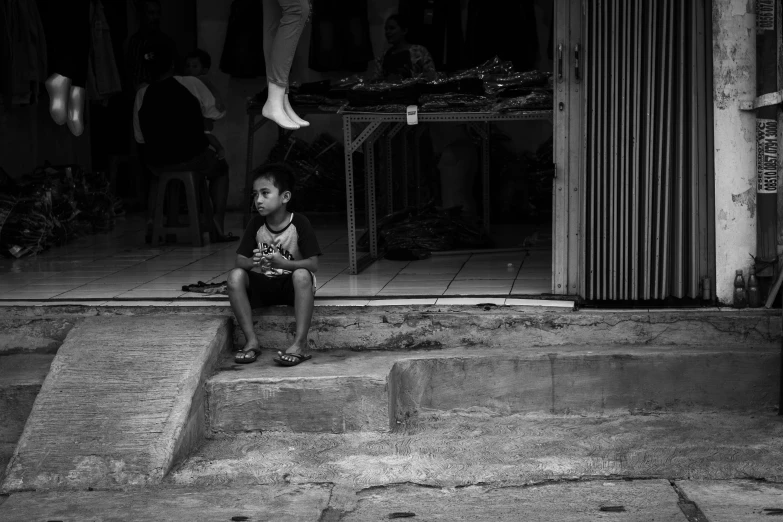 a boy is sitting on the steps near a door