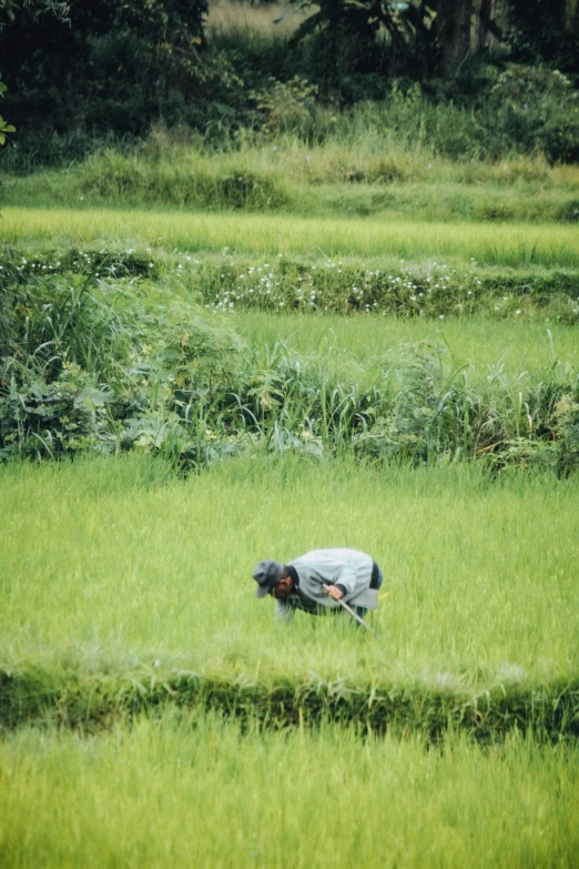 man in grey shirt kneeling down and working on a laptop