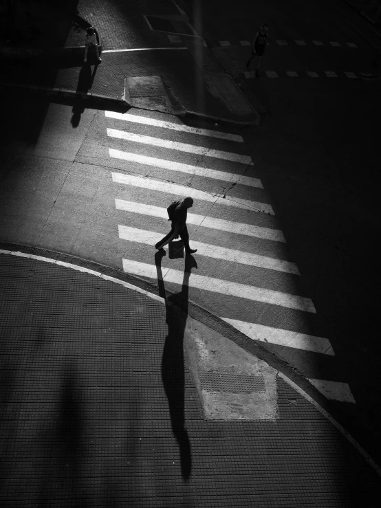 an aerial view of a man crossing the street in the dark