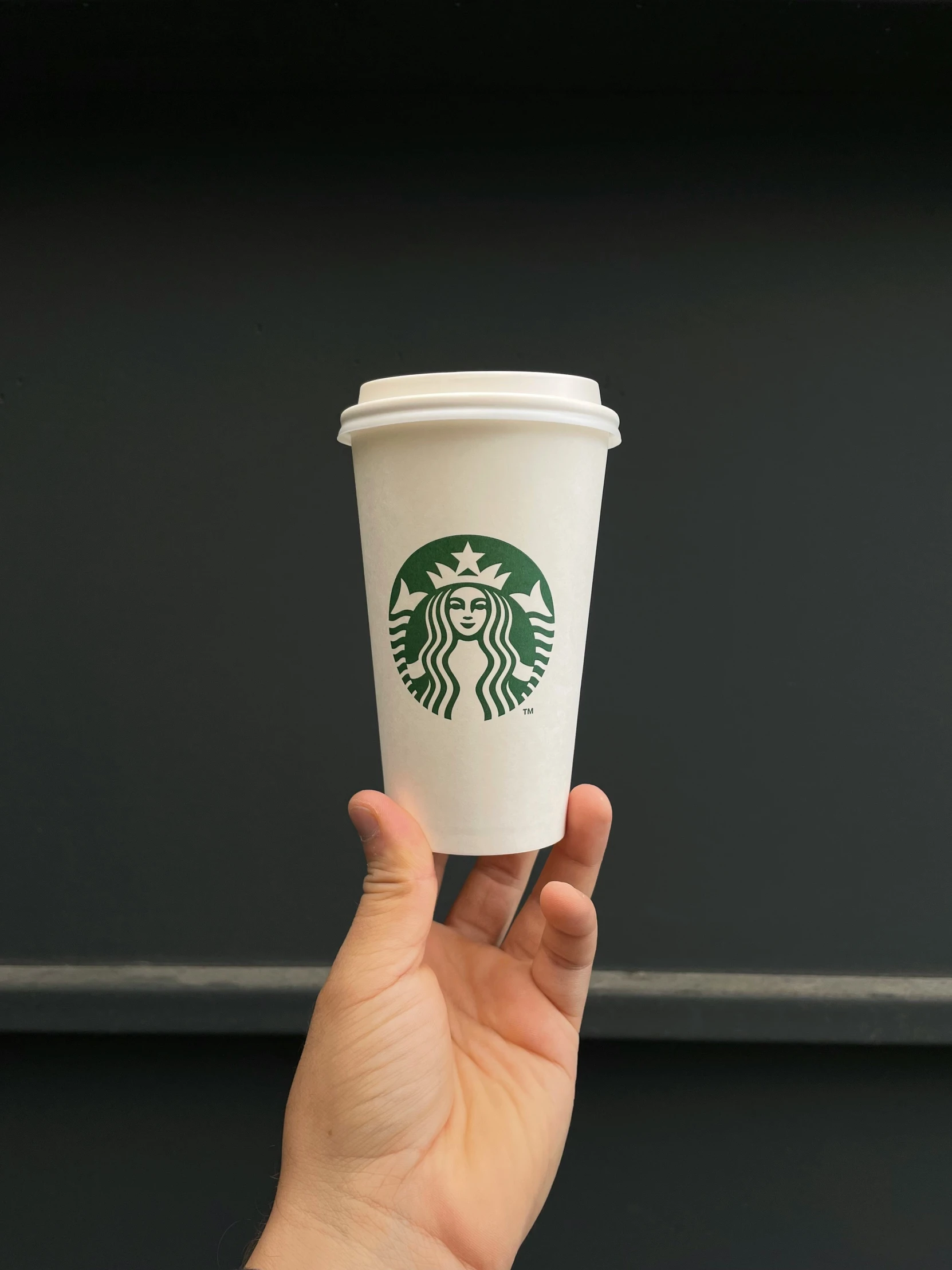 hand holding up starbucks cup while it is green