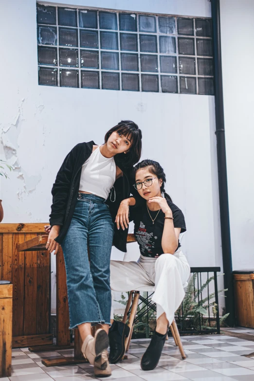 two woman are posing for a picture next to a chair