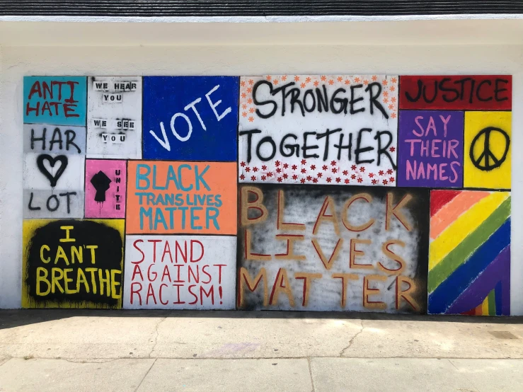 a white wall with colorful words and a peace sign