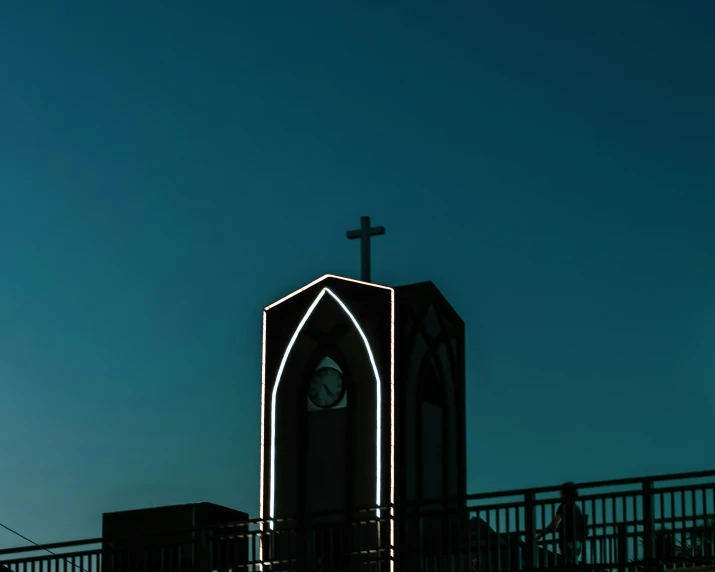 the cross atop a tall church with lights on it