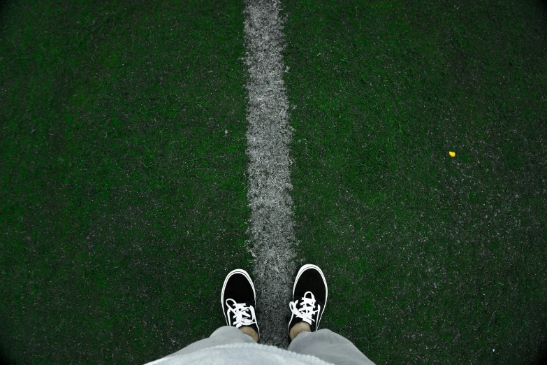 someone with black and white shoes standing on a green grass field