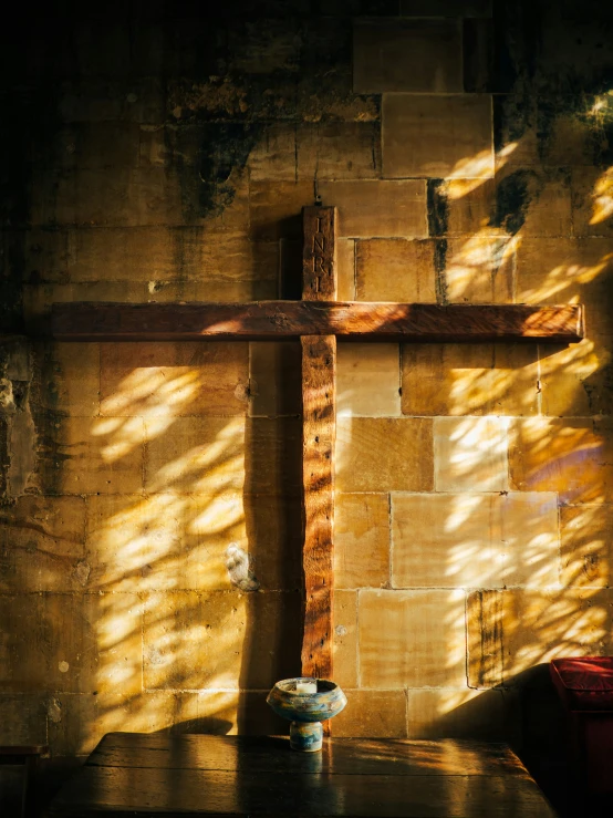 a cross sits in the shadow of a stone wall